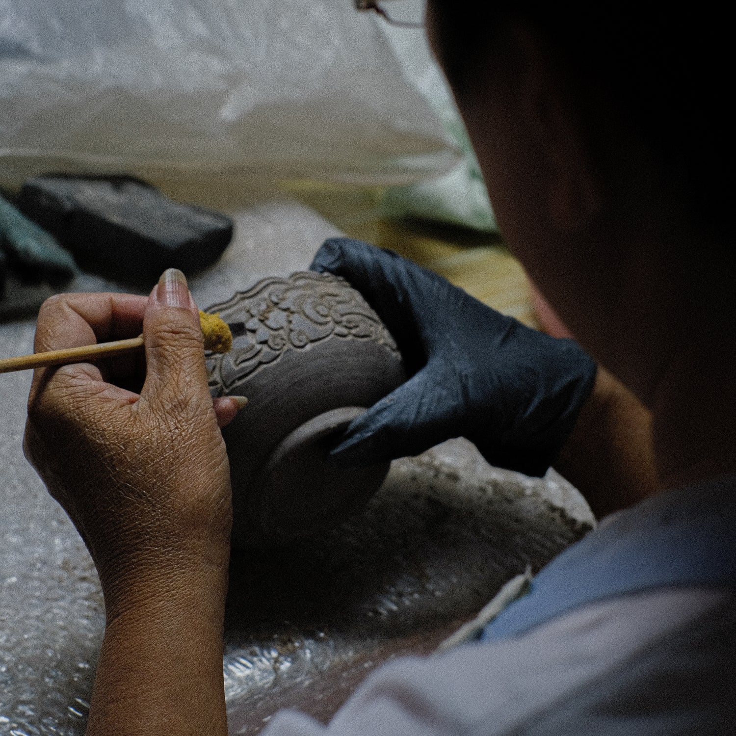 Close-up of woman hand carving a floral pattern onto the edge of a clay bowl