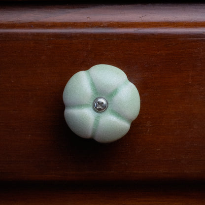 Cabinet Handle in the shape of a Leelawadee Flower, in Green Glaze, mounted to a wooden cabinet.