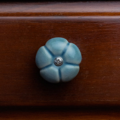 Cabinet Handle in the shape of a Leelawadee Flower, in Blue Glaze, mounted to a wooden cabinet.